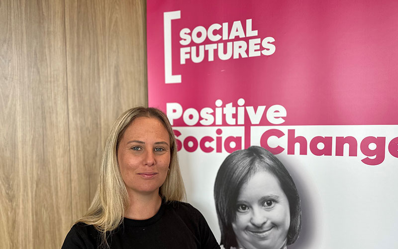 Kiara McBeath woman standing in front of Social Futures banner
