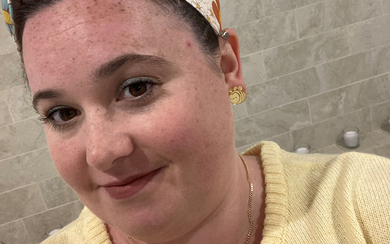 Young woman smiling with brown eyes and dark hair wearing a lemon shirt