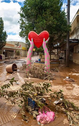 Shows Magellan Street in Lismore, with the You Are Here heart sculpture,  after the flood with mud and fallen muddy trees