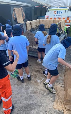 Young teens in a blue school uniform help the SES with sand bagging