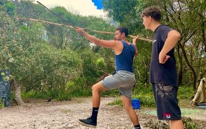 Two 16-17 year old boys in the bush throwing a long spear