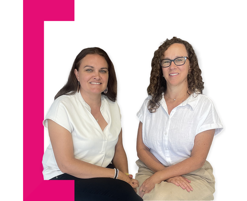 Two women seated and wearing white shirts, one First Nations descent, the other Caucasian and with curly hair